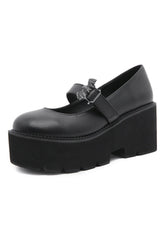 Chunky black shoes with dark bat charm.