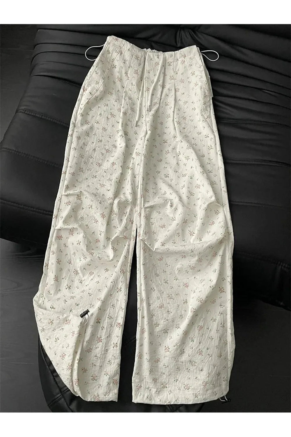 Wide-leg beige pants with floral design.