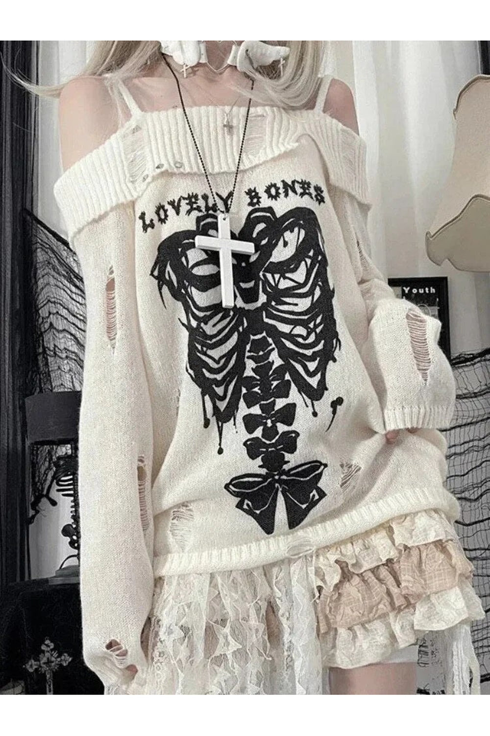 Off-shoulder white sweater with gothic skull motif.