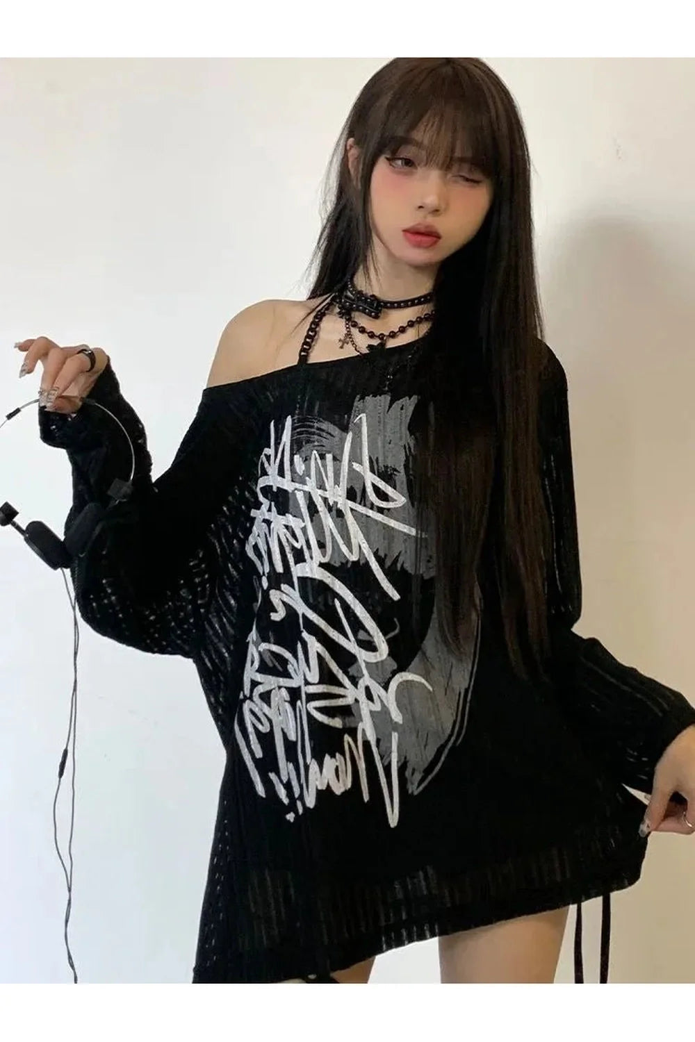 Stylish black off-shoulder sweater with graffiti pattern.