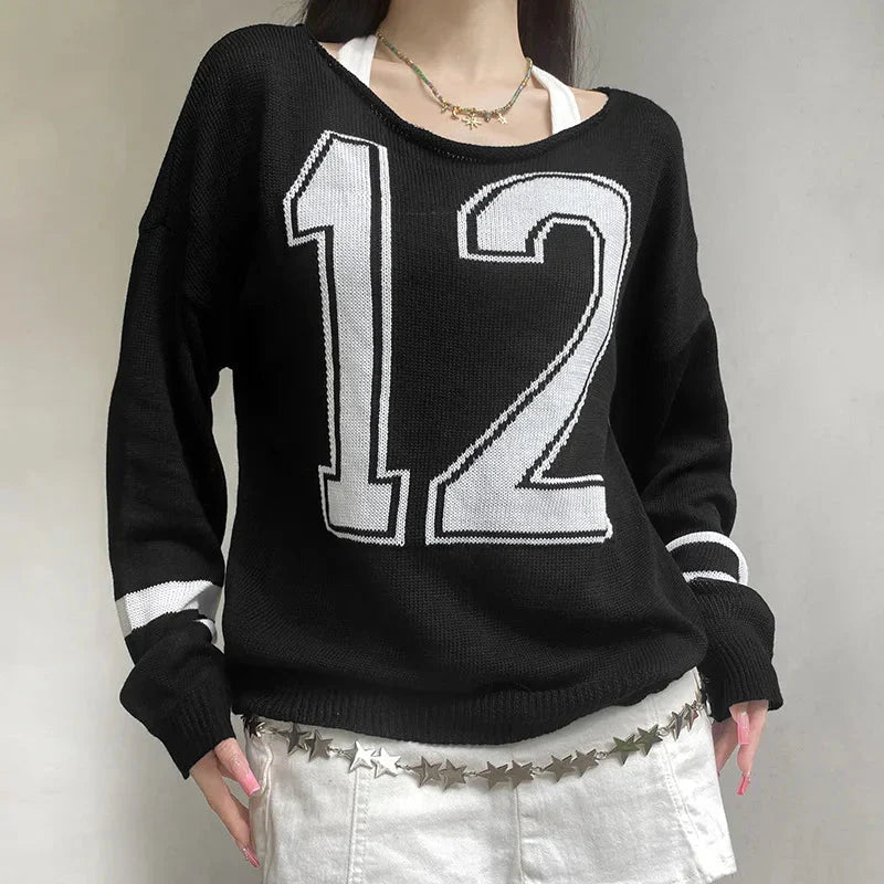 Off-shoulder black sweater with varsity-inspired details.